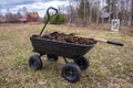 humus in a four-wheeled garden cart. Cloudy spring day