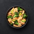 Hunan Chicken in black bowl at dark slate background. Chinese or indo-chinese cuisine takeaway dish Royalty Free Stock Photo