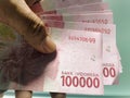 A hundred currency symbol of Indonesia banknote is helding by hand on the white background surface