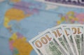 Hundred dollar banknotes. Against the background of a world map. Silhouettes of continents are visible on it