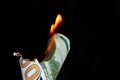 A hundred dollar bill in American US currency is on fire on a black background Royalty Free Stock Photo