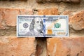 A hundred dollar bill is glued to an old brick wall close-up. Old crumbling red brick wall and cash, us dollar