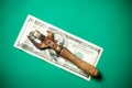 A hundred dollar bill and an old rusty can opener. Green background. Stash concept Royalty Free Stock Photo