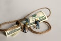 A hundred-dollar bill tied to a rope and miniature people.