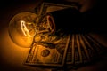 Rising electricity prices. Old light bulb and dollar bills Royalty Free Stock Photo