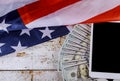 Hundred US dollar bills above digital tablet US flag