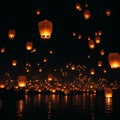 Hundreds of glowing lanterns float into the night sky above a body of water, their Royalty Free Stock Photo