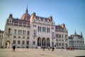 The Hungarian paliament building with walking people around square, Budapest.