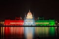 The hungarian Parliament by night lit in national colors In memory of the 1956 war of independence with Danube