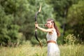 A Hungarian woman in a linen dress standing with a bow on the field in the tall grass Royalty Free Stock Photo