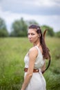 A Hungarian woman in a linen dress standing with a bow in the tall grass Royalty Free Stock Photo