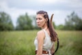 A Hungarian woman in a linen dress standing with a bow in the tall grass Royalty Free Stock Photo