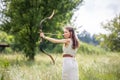 A Hungarian woman in a linen dress standing with a bow in the tall grass Royalty Free Stock Photo