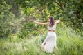 A Hungarian woman in a linen dress standing with a bow in the tall grass Royalty Free Stock Photo