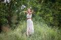 A Hungarian woman in a linen dress standing with a bow in the tall grass Royalty Free Stock Photo