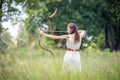 A Hungarian woman in a linen dress standing with a bow in the tall grass Royalty Free Stock Photo