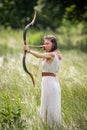 A Hungarian woman in a linen dress standing with a bow in the tall grass Royalty Free Stock Photo