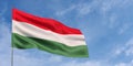 Hungary flag on flagpole on blue sky background. Hungarian flag fluttering in the wind against a sky with clouds. Place for text. Royalty Free Stock Photo