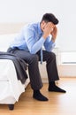 Hungover businessman sitting at edge of bed Royalty Free Stock Photo