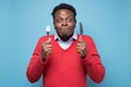 Hungry african man holding fork and knife raised waiting for dinner Royalty Free Stock Photo