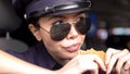 Hungry asian patrolwoman holding burger sitting in police car, greasy food-to-go