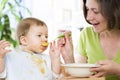 Hungry baby boy eating food next to his mother. Royalty Free Stock Photo