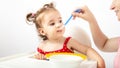 Hungry baby eating healthy kid food, sitting on high chair Royalty Free Stock Photo