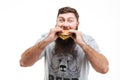 Hungry bearded young man eating hamburger Royalty Free Stock Photo
