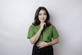 Hungry beautiful Asian woman in green t-shirt holding her stomach think of tasty food isolated over white background