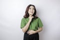 Hungry beautiful Asian woman in green t-shirt holding her stomach think of tasty food isolated over white background