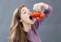 Hungry beautiful girl eating up tomatoes with appetite and greed