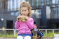 Hungry beautiful serious child with appetite eating fast food, drinking water.