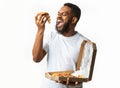 Hungry Black Guy Eating Pizza Slice Standing Over White Background
