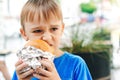 Hungry boy eating a burger at outdoors cafe. Cute child eating fast food. Childhood, unhealthy food concept Royalty Free Stock Photo