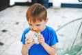 Hungry boy eating a burger at outdoors cafe. Cute child eating fast food Royalty Free Stock Photo