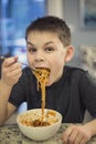 Hungry and Excited boy taking a huge bite of spaghetti