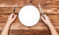 Hungry child waiting for meal. Child's hands holding fork and knife over table with empty dish. Top view Royalty Free Stock Photo