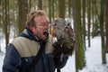 Hungry falconer with tawny owl on his glove, eating chicken reward