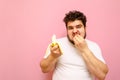 A hungry fat guy on a diet eagerly eats a banana and looks into the camera with an emotional face. Funny young overweight man