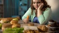 Hungry fat lady eating carrot, dreaming about donut and fast food, healthy diet Royalty Free Stock Photo