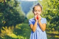 Hungry female kid is ready to taste an autumnal apple, enjoying annual harvest in apple-trees garden.