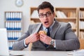 The hungry funny businessman eating junk food sandwich