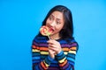 Hungry funny woman bite delicious colorful lollipop