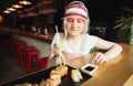 A hungry girl with chopsticks in her hands takes a roll of sushi from her plate and looks for food with appetite.Teen girl in pink Royalty Free Stock Photo