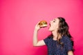 Hungry girl with opened mouth eating big hamburger.