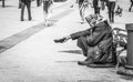 Hungry homeless beggar woman beg for money on the urban street in the city from people walking by, social documentary concept blac Royalty Free Stock Photo