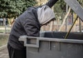 Hungry homeless man rummaging in trash can looking for food Royalty Free Stock Photo