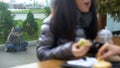 Hungry homeless sitting on street outside restaurant, female having lunch cafe