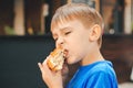 Hungry kid eating a burger at outdoors cafe. Cute child eating fast food. Childhood, unhealthy food concept Royalty Free Stock Photo