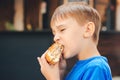 Hungry kid eating a burger at outdoors cafe Royalty Free Stock Photo